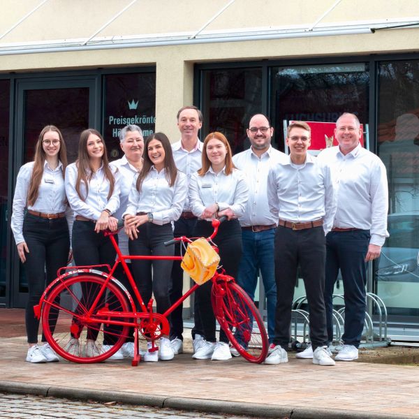 Das Team von Hörluchs Hörgeräte vor dem Fachgeschäft in Pommelsbrunn. Im Vordergrund ist ein rotes Fahrrad zu sehen