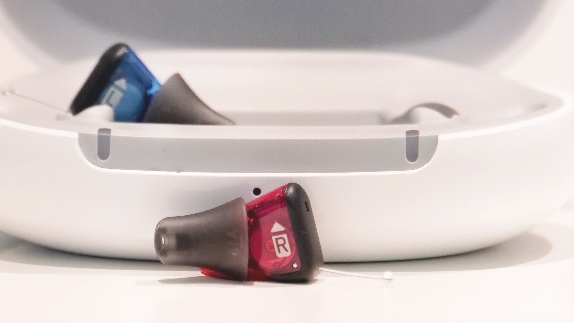 Nahaufnahme der neuen Signia Silk Charge & Go IX Akku-Im-Ohr-Hörgeräte an der EUHA 2023. Zu sehen ist die Ladeschale mit einem blauen Gerät und vorne das rote Gerät.